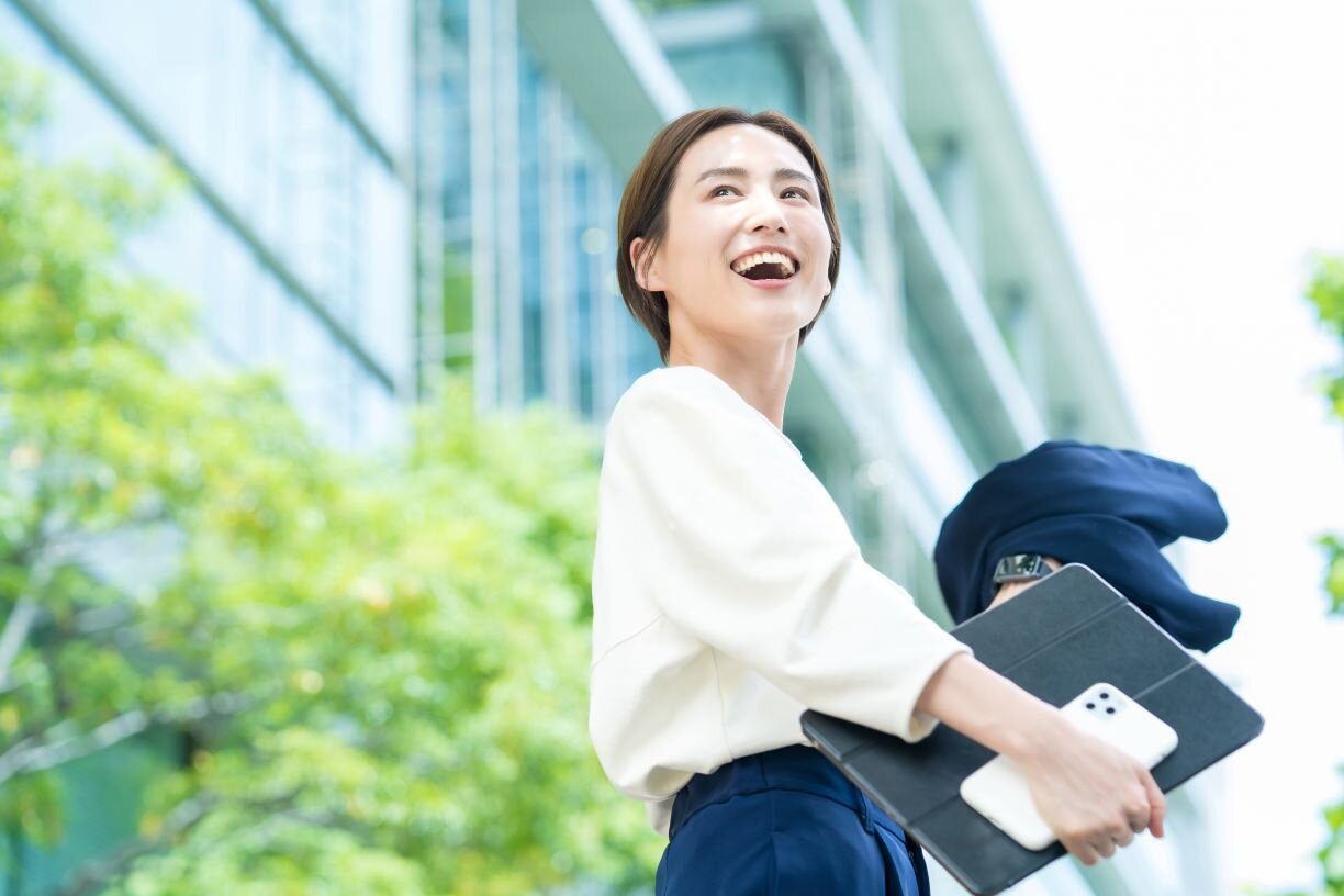 オフィス街に立つ笑顔の女性