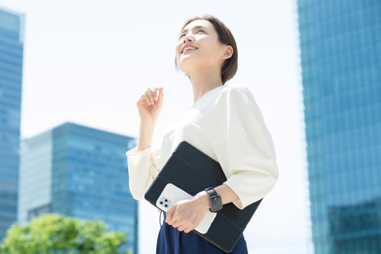 オフィス街に立つ笑顔の女性